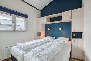 A bedroom with a bed, a window, and built-in storage.