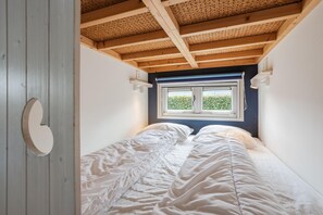 Una habitación pequeña con una cama individual, una ventana con vistas a zonas verdes y un techo de madera.