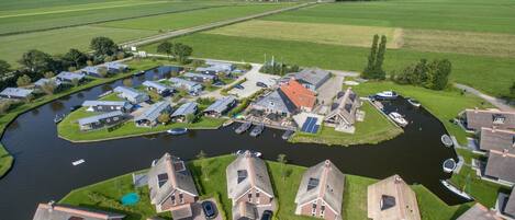 Un quartier résidentiel situé au bord d’un canal, avec des maisons, des bateaux et un petit quai.