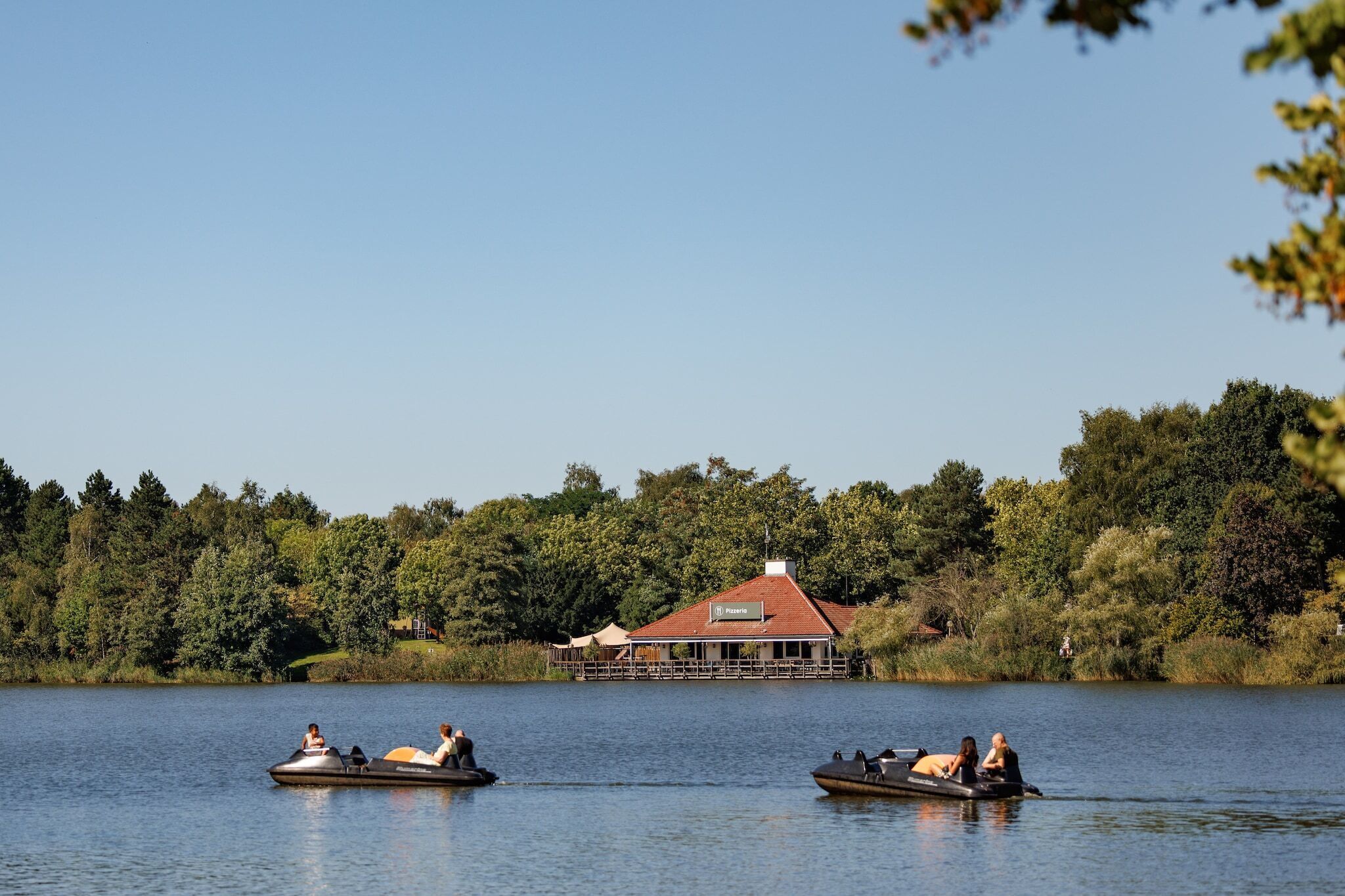 Uitzicht op een meer met een huis en twee boten op het water.