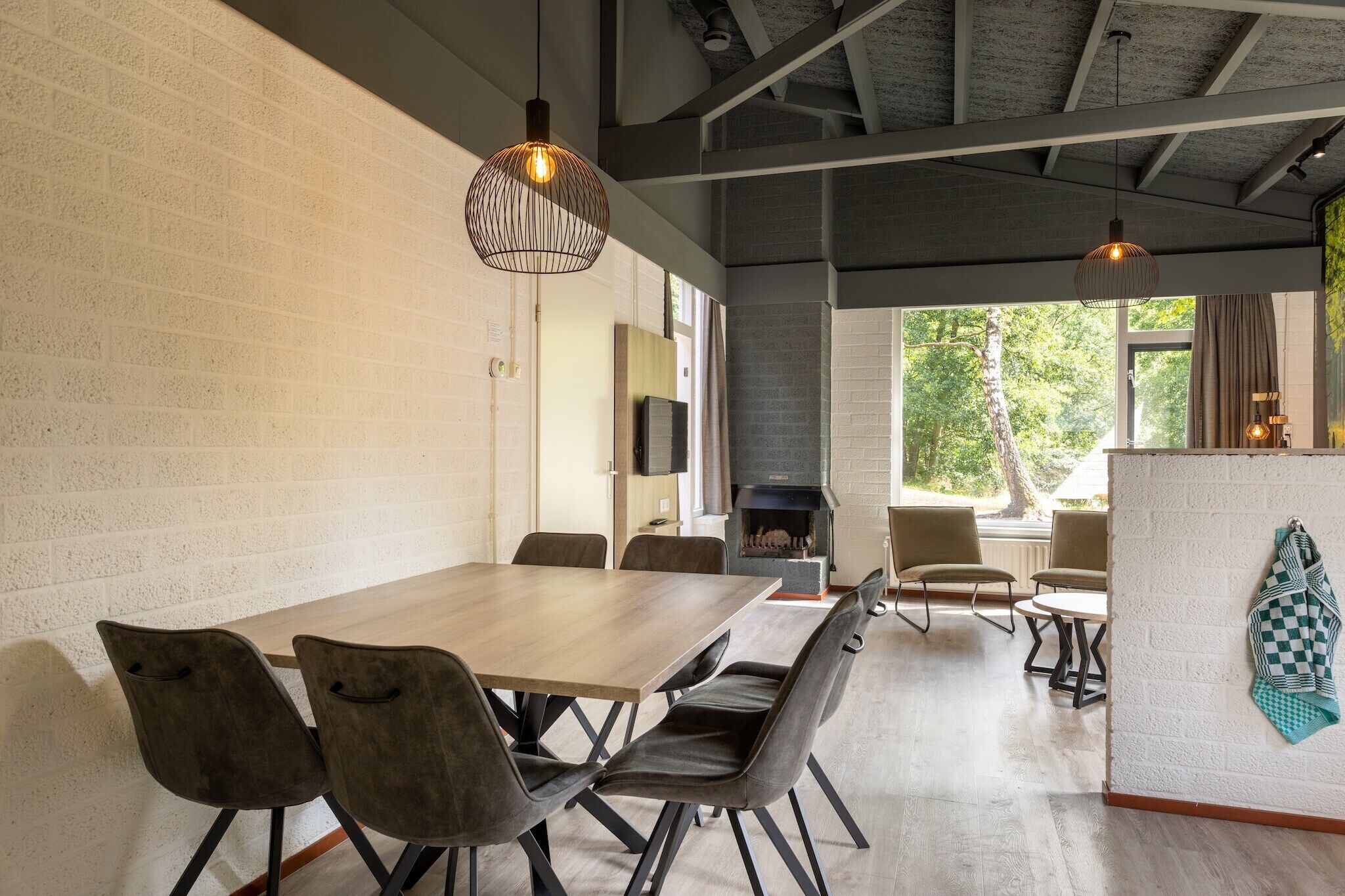Un espace repas moderne avec une table et des chaises en bois, un mur en briques et une cheminée.