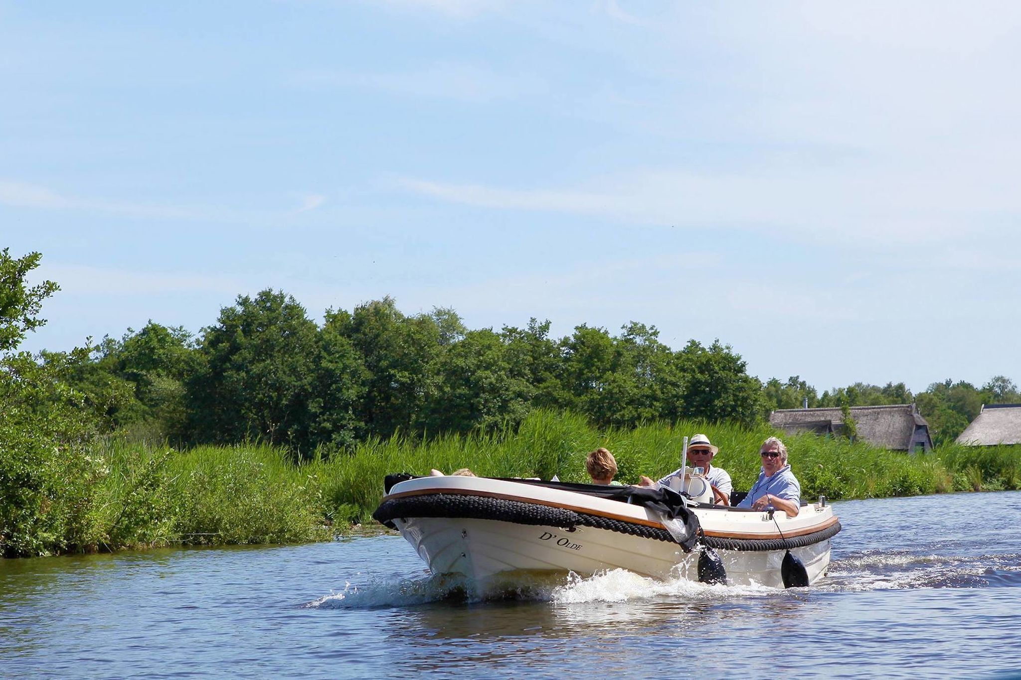 Una barca con tres personas navegando por un río rodeado de vegetación.