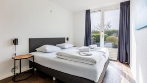 Ein modernes Hotelzimmer mit einem großen Bett, einem Nachttisch und Blick ins Freie.