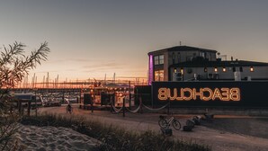 Ein Yachthafen mit Booten, eine Neonreklame für 'BUECHLIN' und ein Gebäude mit einem Balkon.