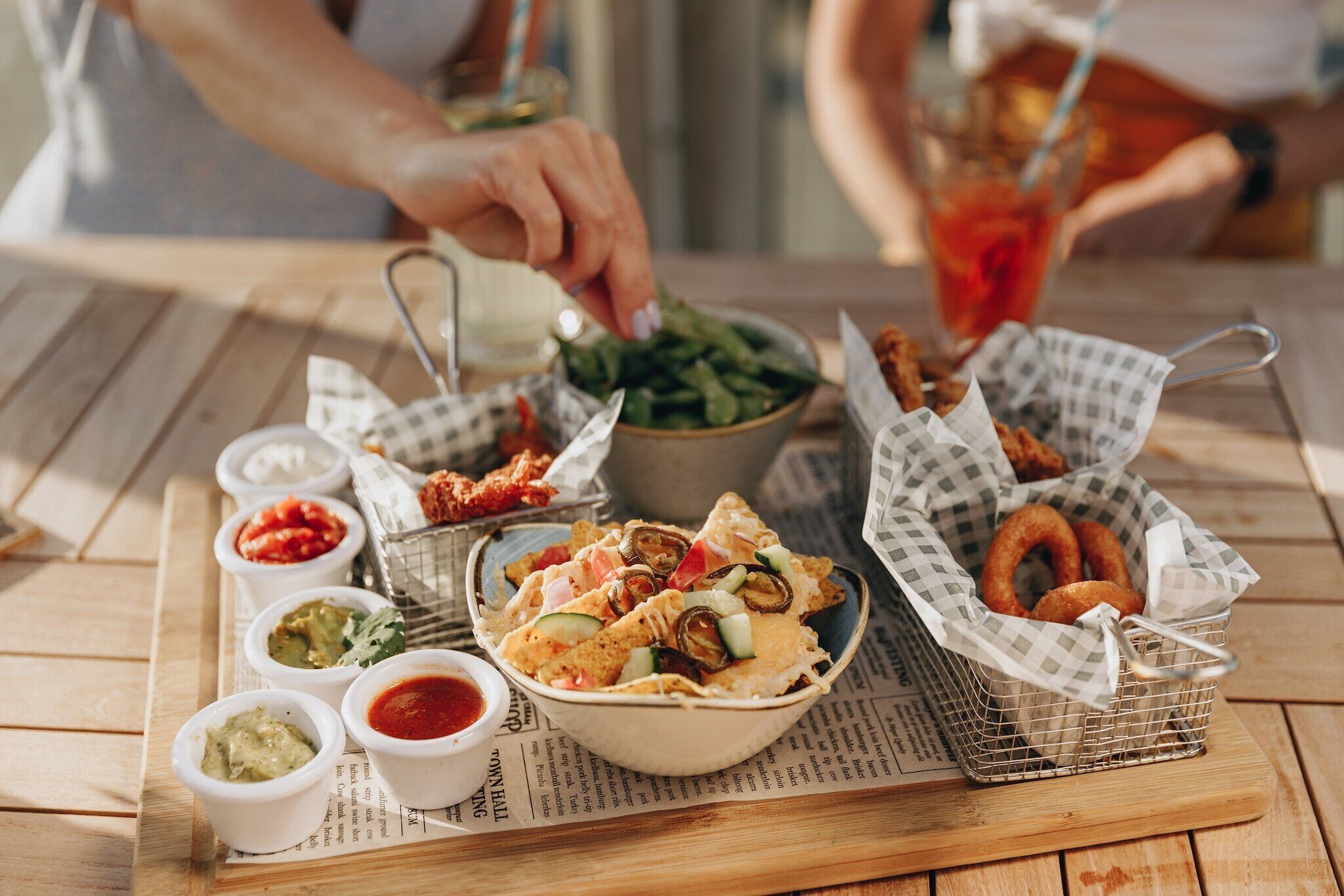 Uma mesa com nachos, molhos para acompanhar e anéis de cebola.
