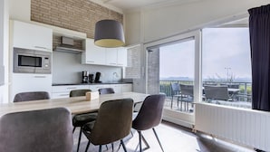 Eine moderne Küche mit Essbereich, großen Fenstern und Blick ins Freie.