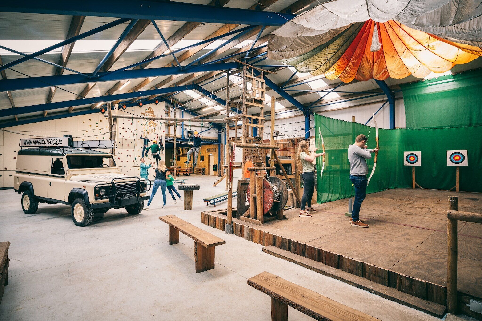 An indoor climbing facility with wooden structures, a vehicle, and targets.