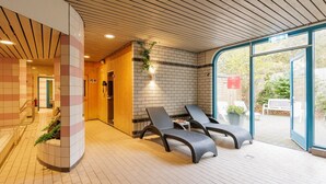 Un espacio interior moderno para relajarse, con sillones, una pared de ladrillo y una puerta de cristal que da al exterior.