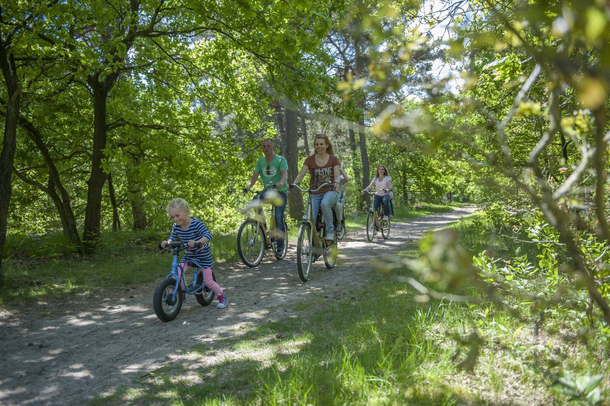 A group of people riding bicycles on a dirt path surrounded by trees.