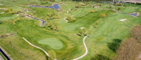 An aerial view of a golf course with multiple fairways, sand traps, and water hazards.