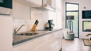 Une cuisine moderne avec des meubles blancs, un évier en acier inoxydable et une machine à café.