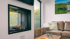 Un salon moderne avec une grande fenêtre, une table basse en bois, un canapé en cuir marron et un tableau accroché au mur.