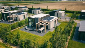 Un quartier résidentiel moderne composé de plusieurs maisons individuelles, chacune dotée de grandes fenêtres, de panneaux solaires et de jardins bien entretenus.