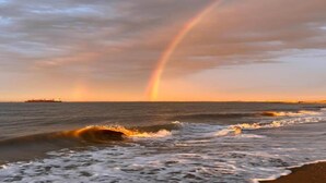 Een strandgezicht met golven en een regenboog.