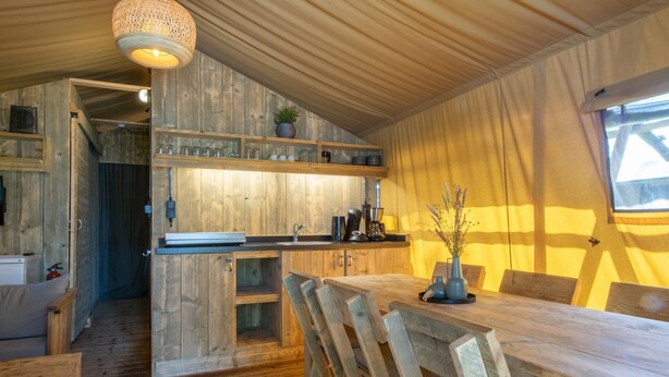 A rustic wooden interior with a dining area, kitchen, and a cozy seating space.
