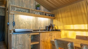 A rustic wooden kitchen with a built-in sink, shelves with glassware, and a wooden dining table.
