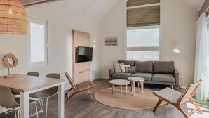 Una sala de estar moderna con un sofá gris, una mesa de comedor de madera y sillas de mimbre.