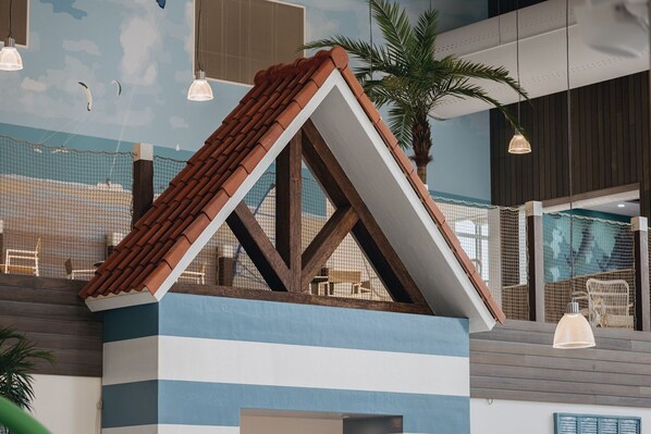 A model of a building with a sloped roof, wooden beams, and a blue and white color scheme.