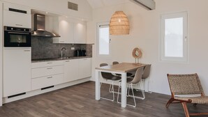 Una cocina moderna con armarios blancos, horno empotrado y una lámpara colgante grande.