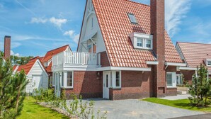 Una hilera de casas modernas de ladrillo con tejados de tejas rojas, detalles blancos y un césped cuidado.