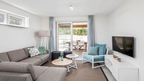 Un salon moderne comprenant un canapé, une table basse, un téléviseur et un balcon avec une table et des chaises.