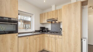 Eine moderne Küche mit Holzausstattung, integriertem Backofen, Kaffeemaschine und einem Fenster.