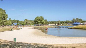 Ein Park am Seeufer mit Sandstrand, einer Anlegestelle und mehreren Zelten.