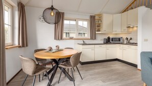 Een moderne keuken met een eethoek, met een ronde houten tafel, stoelen en een hanglamp.