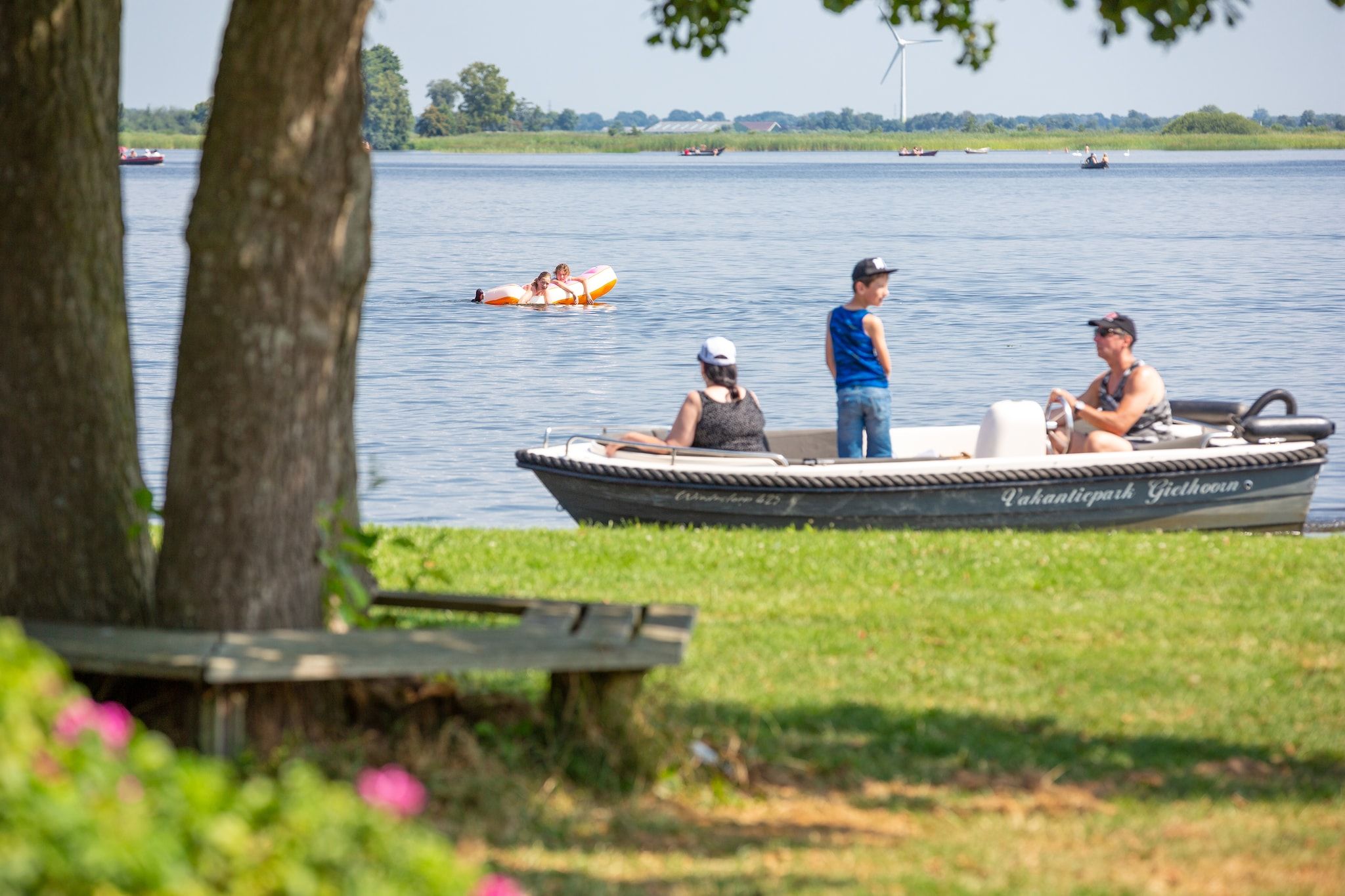 A boat named "Pachamtecpark Gidhoorn" on a lake with people on board.