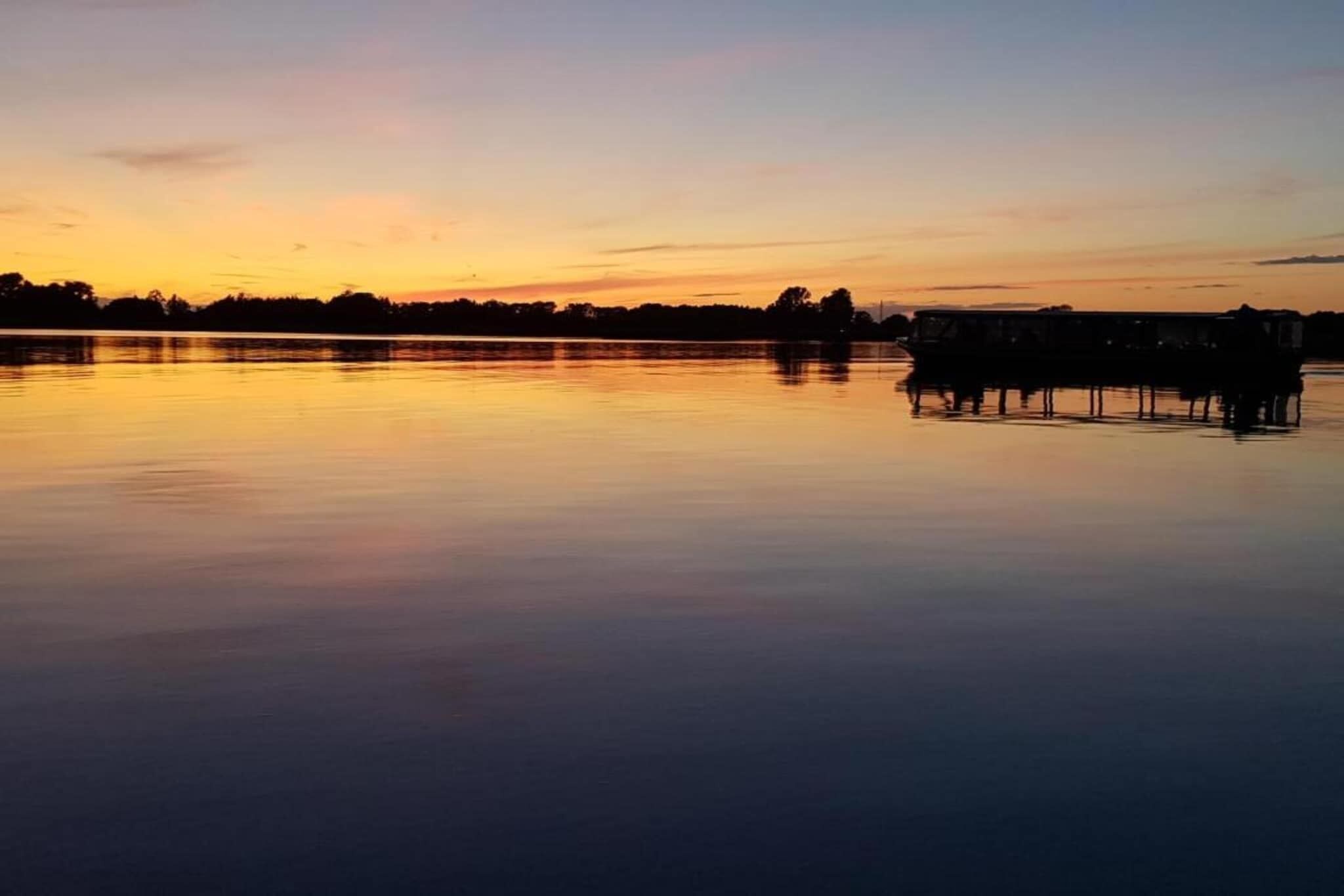 Un lac paisible au coucher du soleil, avec un quai et un bateau à rames.