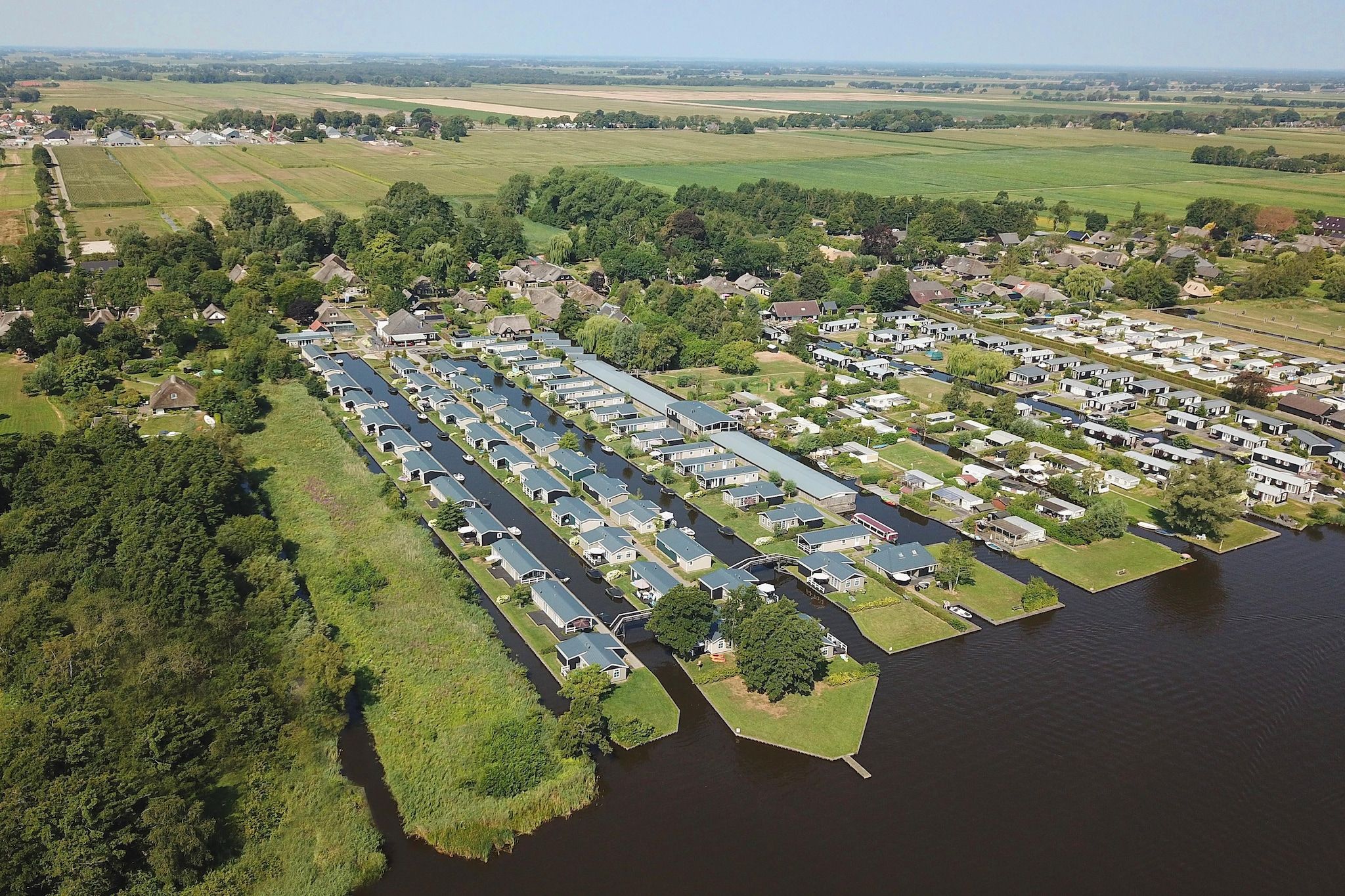 An aerial view of a residential area with houses and mobile homes along a riverbank.