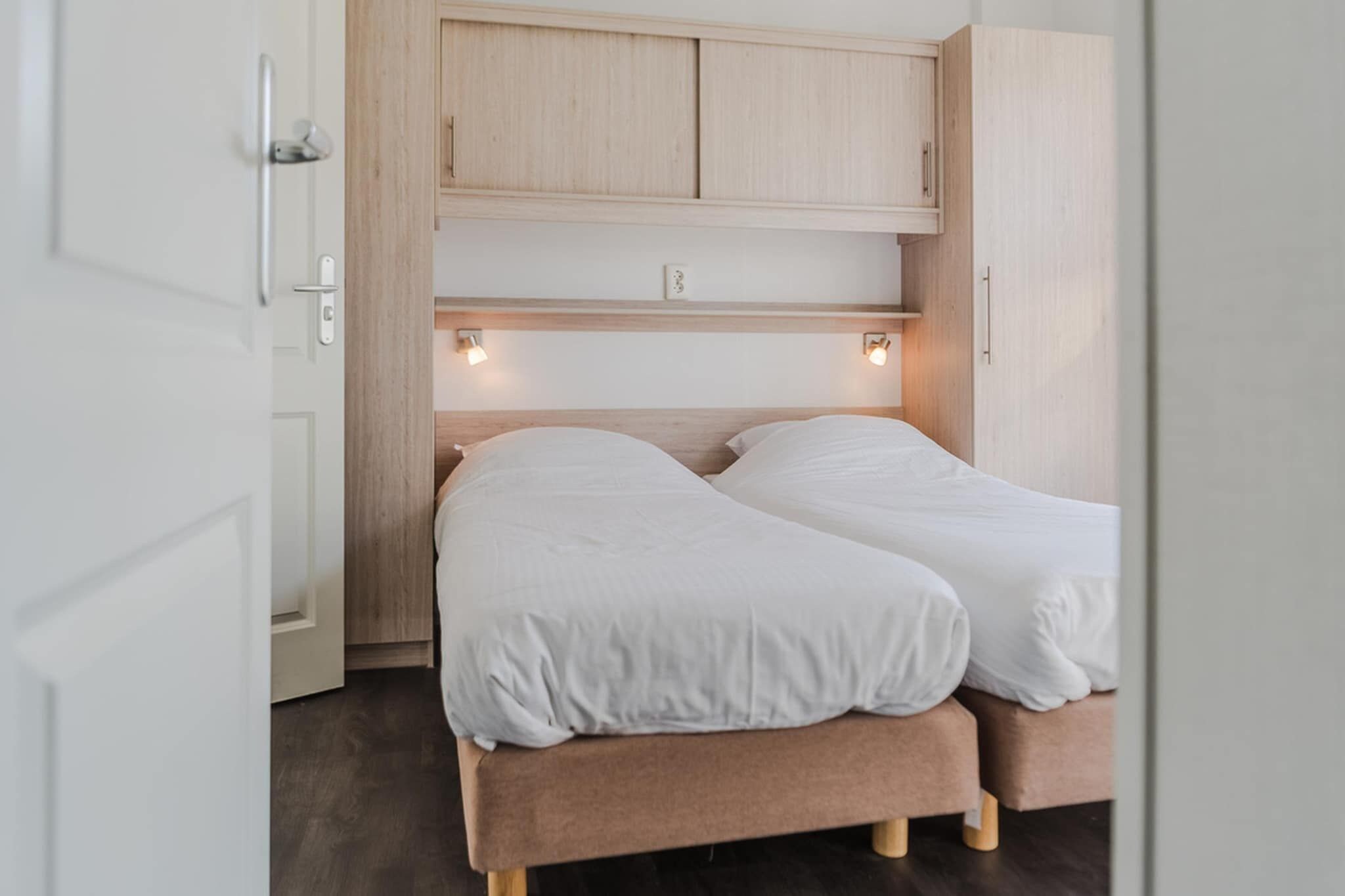 A bedroom with a bed, wooden headboard, and built-in lighting.