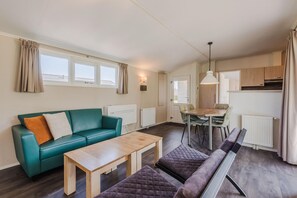 Un salon moderne avec un canapé vert, une table basse en bois et un coin repas comprenant une table et des chaises.