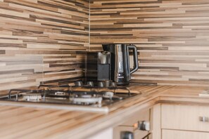 Une cuisine au design moderne, équipée d’une cuisinière à gaz et d’une machine à café.