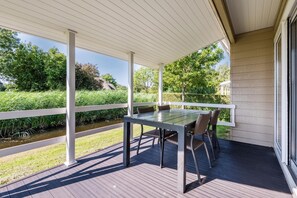 Une terrasse extérieure avec une table et des chaises, une vue sur une rivière et un bâtiment en arrière-plan.