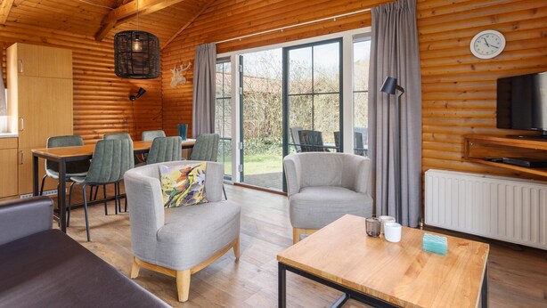 Een gezellig, blokhut-achtig verblijf met houten wanden, een eethoek en een televisie.