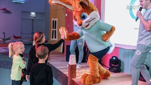 A stage with a rabbit mascot, a man holding a microphone, and children interacting.