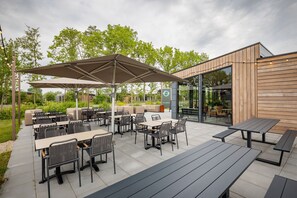 Relax in a serene outdoor space surrounded by lush greenery and trees, with seating options and a shaded area.