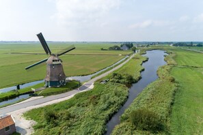 Traditional windmill situated in a rural landscape with a paved pathway leading to its doorstep.