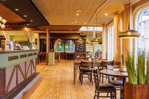 A cozy restaurant interior with wooden floors, a bar area, and several dining tables and chairs. - Woodland Glamping Getaway (Borger)