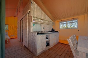 A compact kitchen with wooden cabinets, a built-in stove, and a window providing natural light. - Woodland Glamping Getaway (Borger)