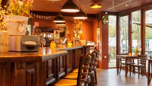 Eine Bar mit Holzküchenmöbeln, Pendelleuchten und Blick ins Freie.