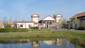 A building with a central entrance, a small pond in front, and a clear sky.