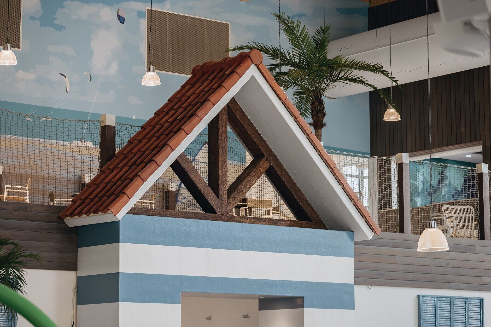 En model af et hus med skråt tag, træbjælker og en facade med striber.