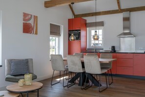 Uma cozinha moderna com armários vermelhos, uma mesa de jantar com cadeiras e luminárias pendentes.