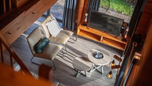 Een gezellige kamer met een houten vloer, twee stoelen, een kleine tafel en een televisie op een houten dressoir.