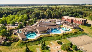Luchtbeeld van een hotel met meerdere gebouwen, een groot zwembad en omliggend groen.