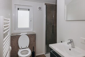 Et badeværelse med toilet, vask og brusebad.