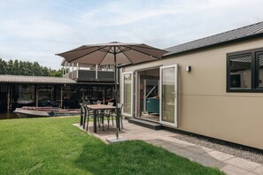 Et moderne hus med terrasse, spisebord og parasol.
