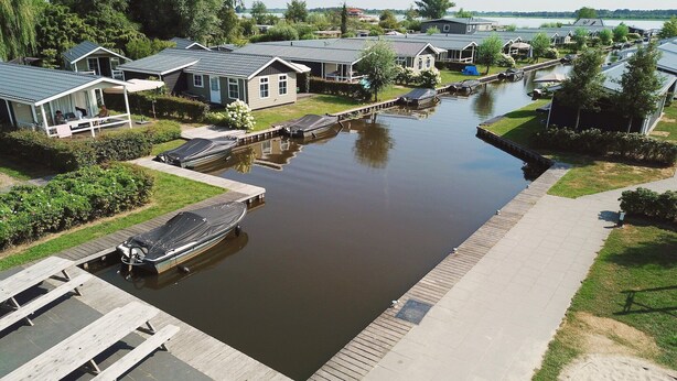Un quartier résidentiel situé au bord d’un canal, avec des maisons, un quai et un bateau.